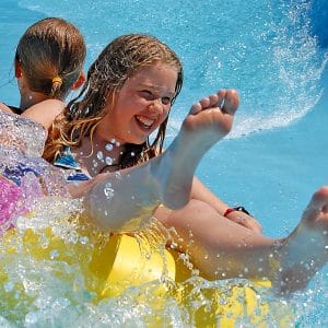 Two children in swimming going down a water slide